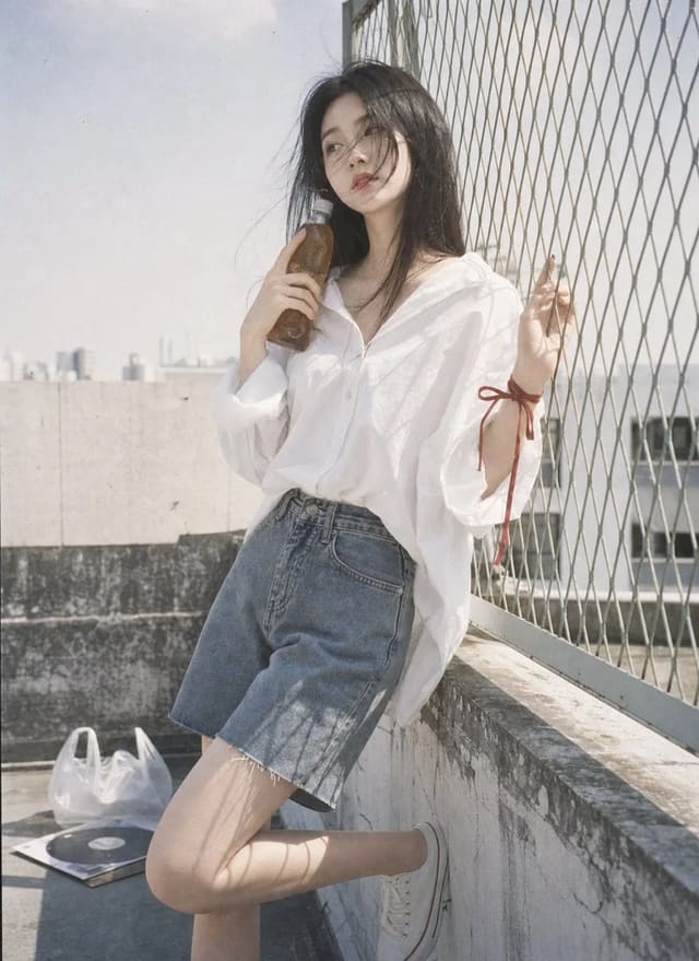 Rooftop portrait with oversized white shirt and denim Bermuda shorts