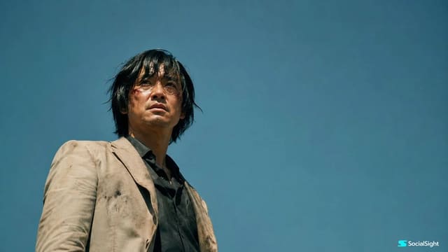 Cinematic low-angle film still of a wounded man under a vast blue sky