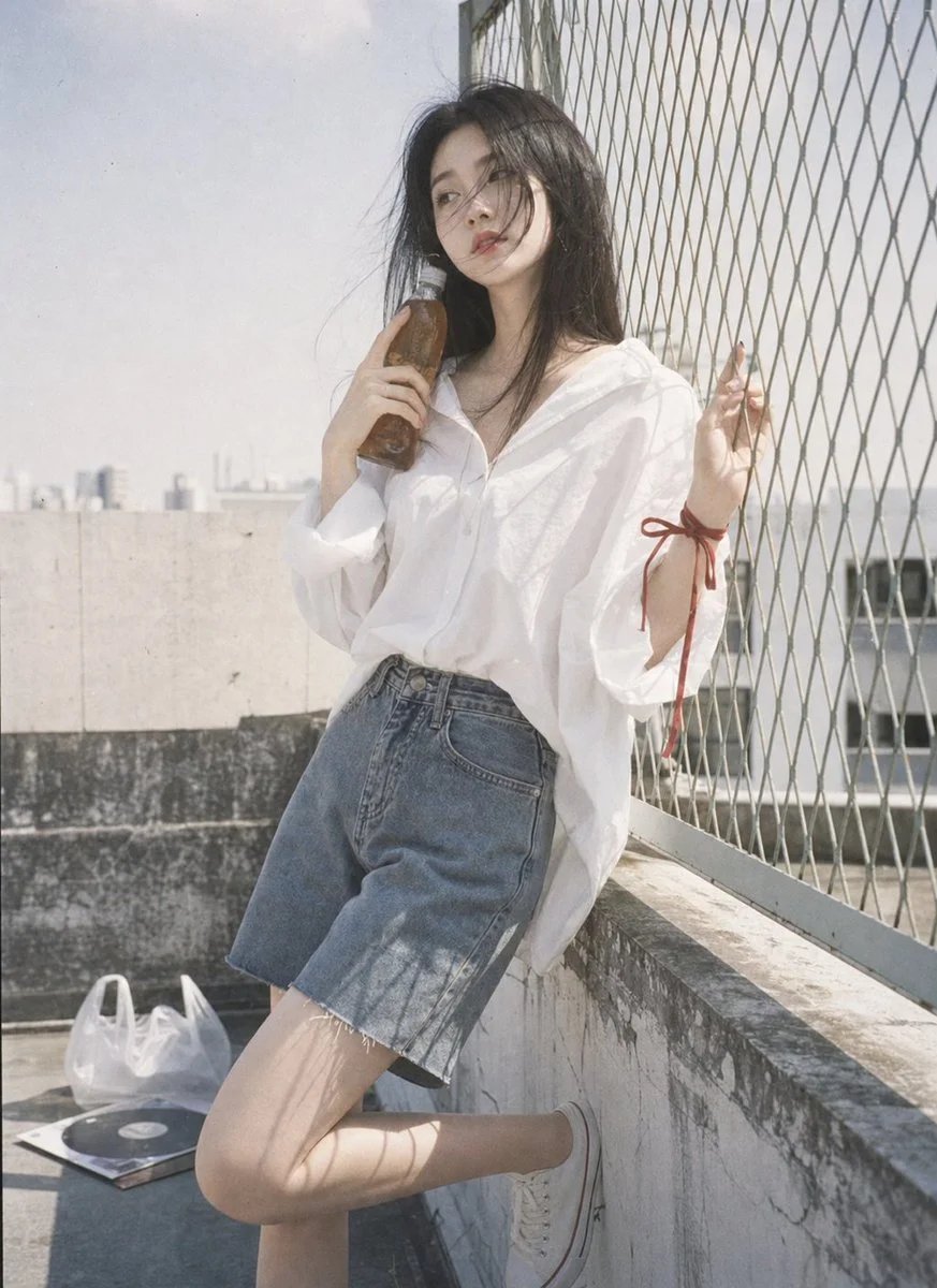 Rooftop portrait with oversized white shirt and denim Bermuda shorts