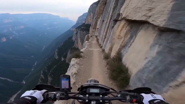 First-person POV motorcycle rider on razor-thin cliff path