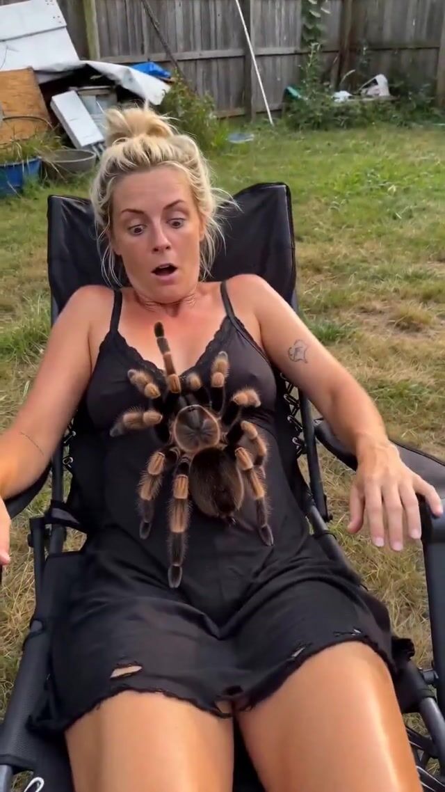 Woman affectionately pets giant tarantula in messy backyard